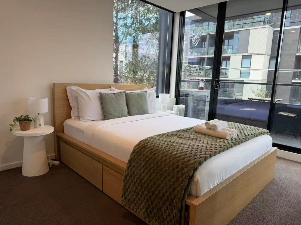 Freshly prepared bedroom with oak furniture, white linen and soft green accents